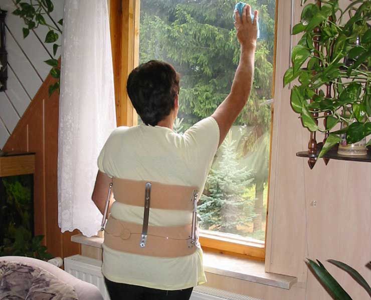 Eine Frau in Orthese putzt ein Fenster mit einem Schwamm