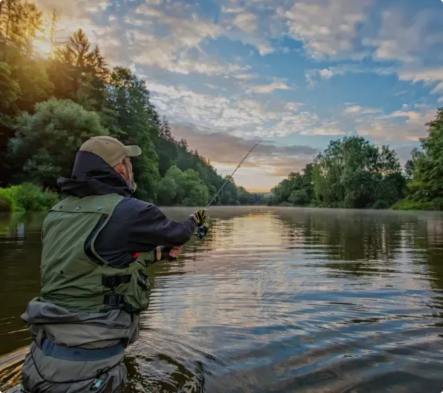 A man is fishing in a river with a fishing rod.