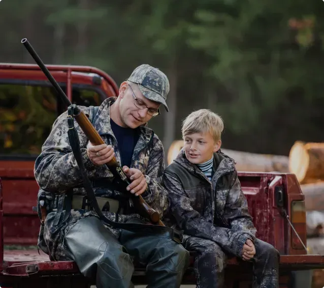 A man and a boy are sitting in the back of a truck.