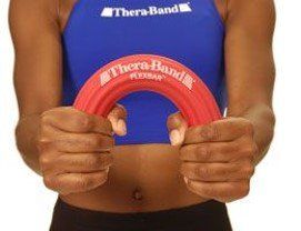 A woman is holding a red thera band in her hands.