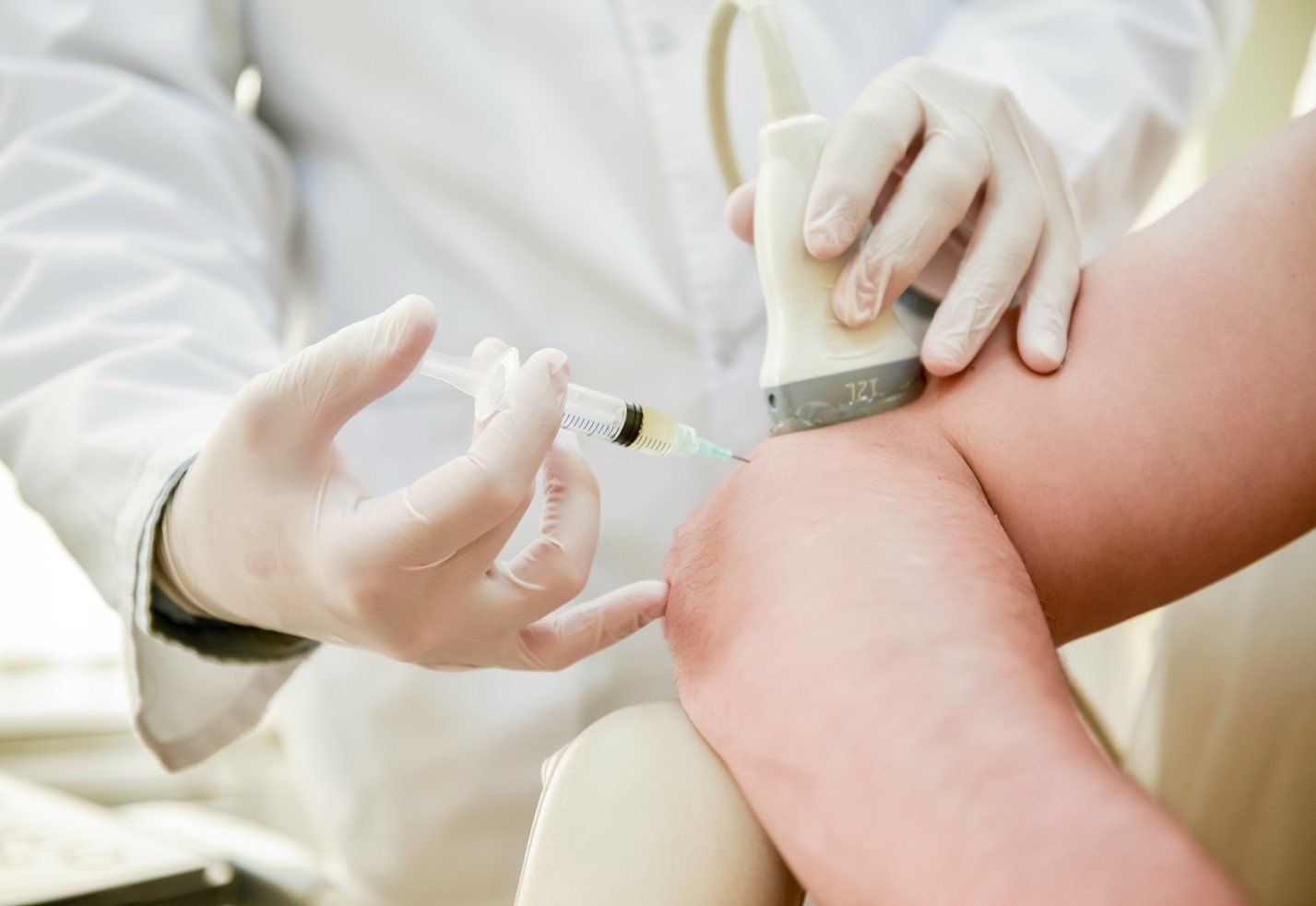 A doctor is giving a patient an injection in their knee.