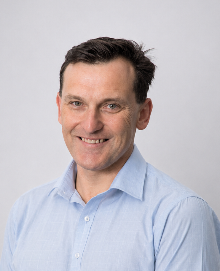 Smiling man in a light blue shirt against a plain gray background