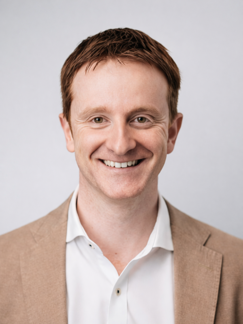 A man in a suit and white shirt is smiling for the camera.