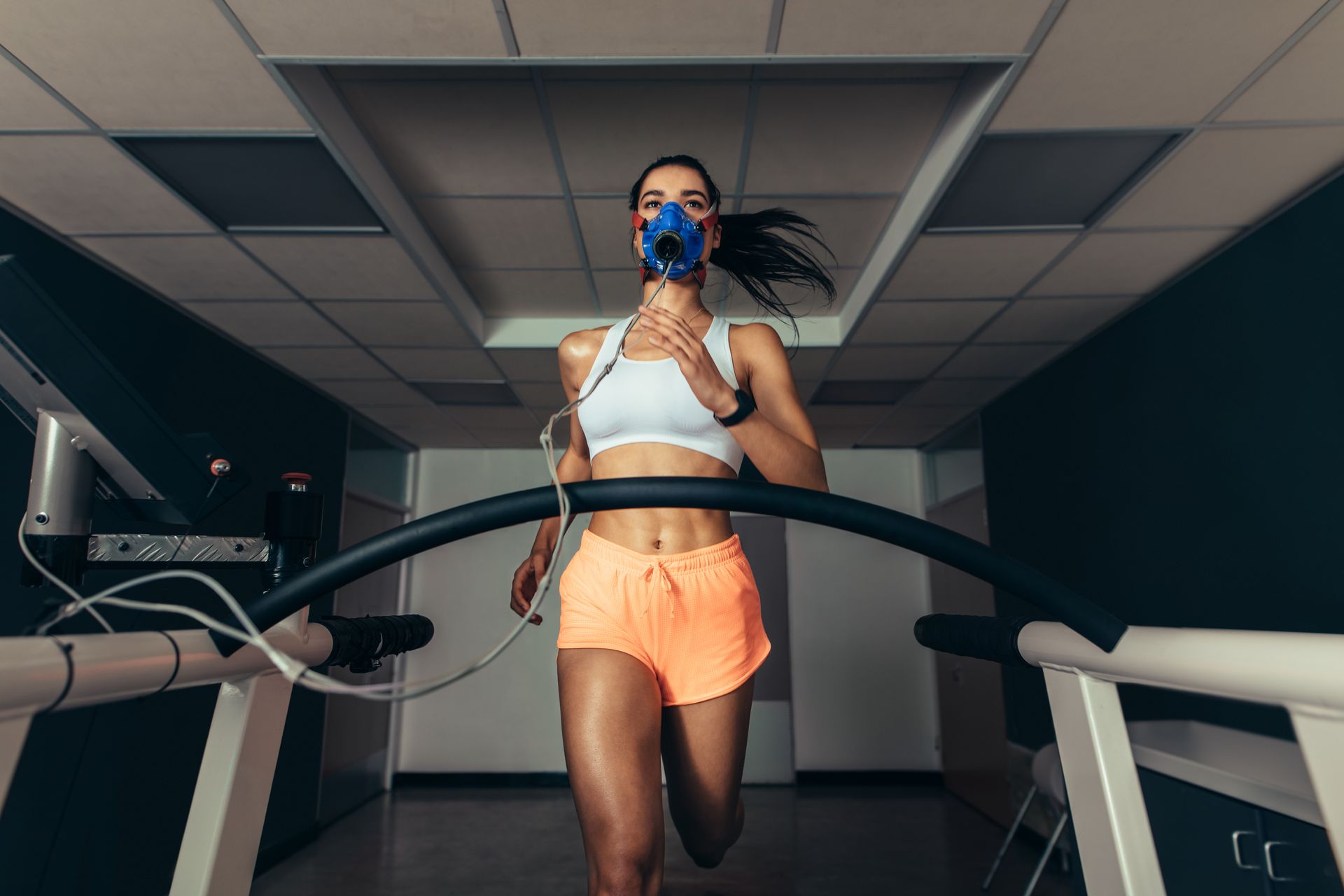 A woman wearing an oxygen mask is running on a treadmill to do a VO2 max test