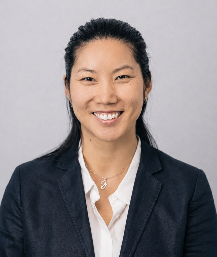 Smiling professional in navy blazer and white shirt against a light gray background