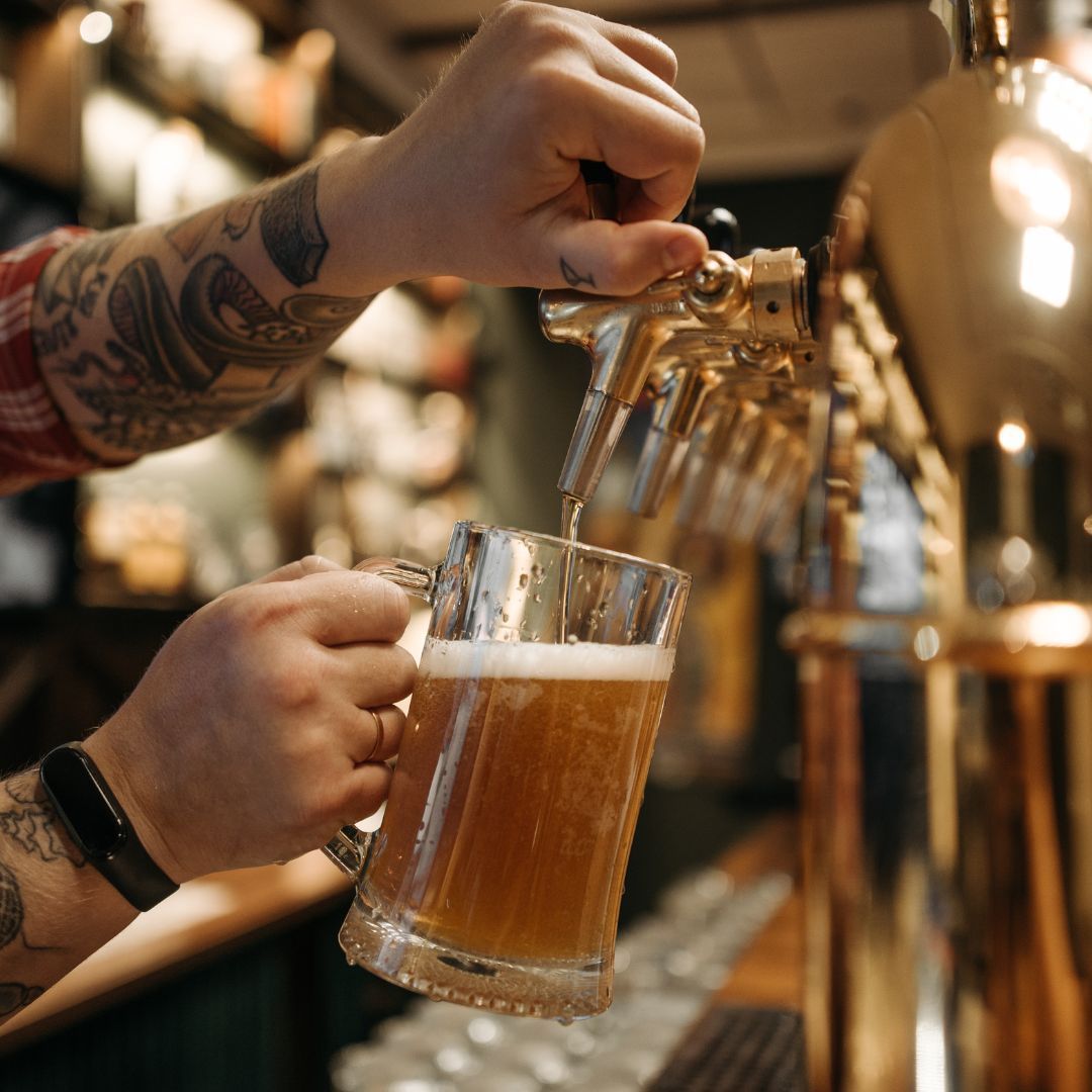 A man is pouring beer into a glass at a bar.
