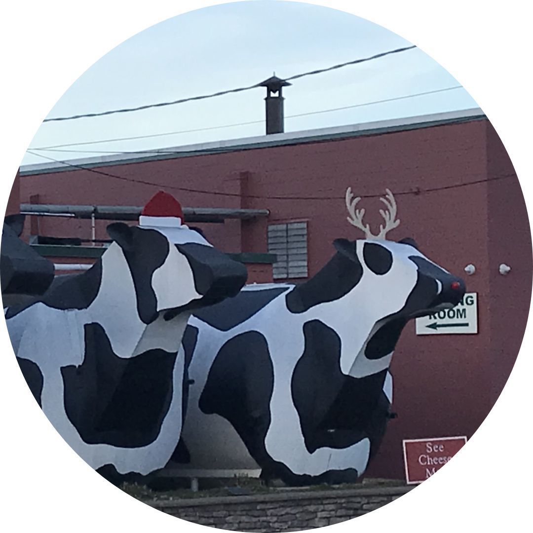 A statue of a cow wearing a santa hat and antlers
