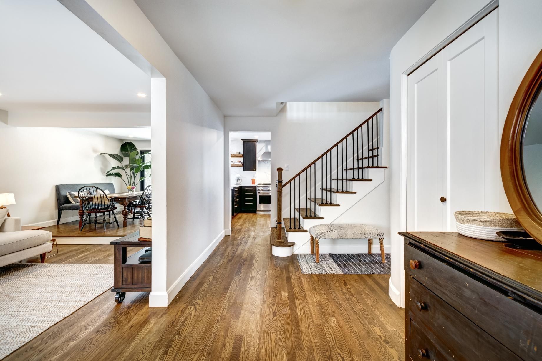 A hallway in a house with hardwood floors and stairs.