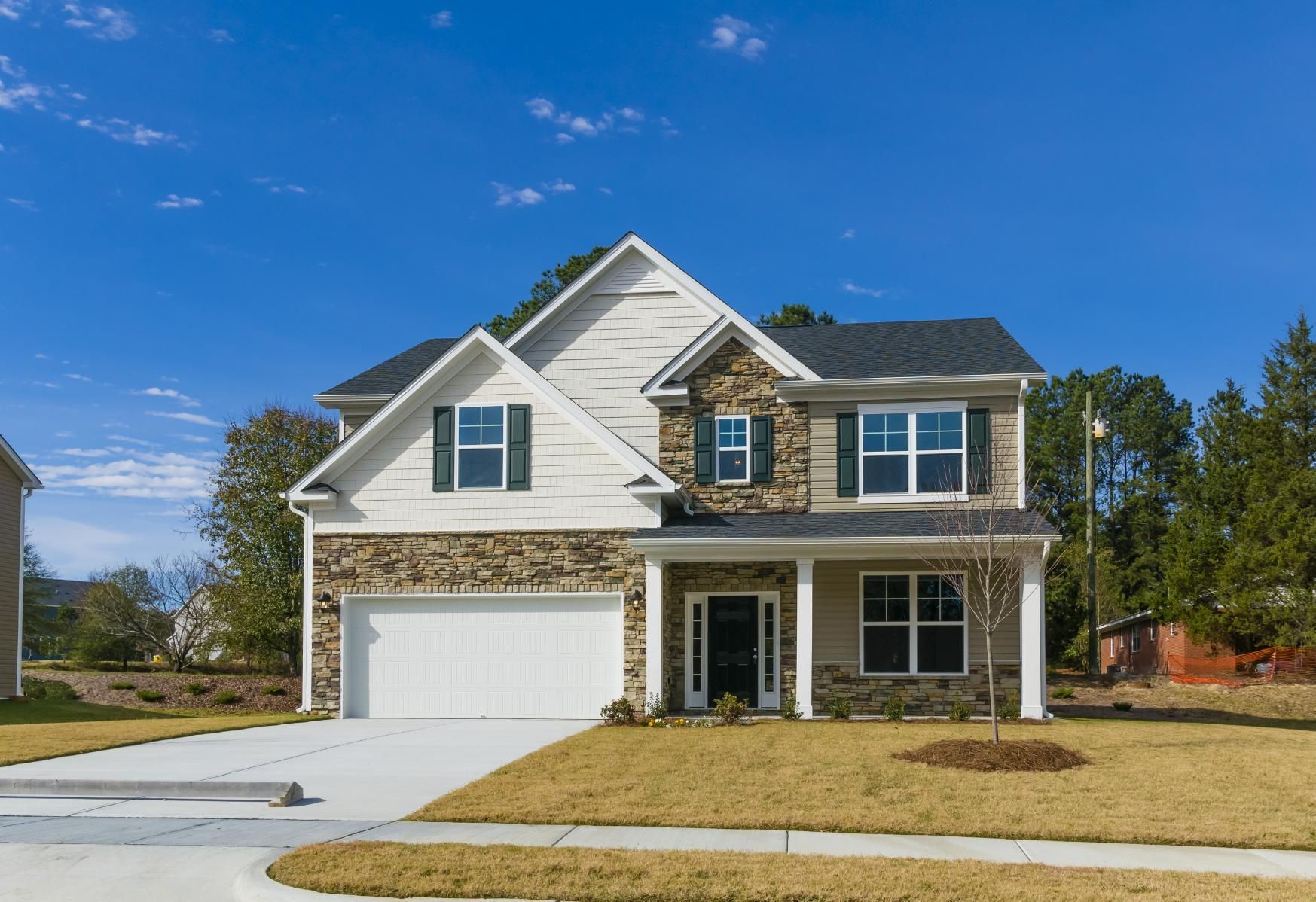 A large white house with a stone facade is sitting on top of a lush green hillside.