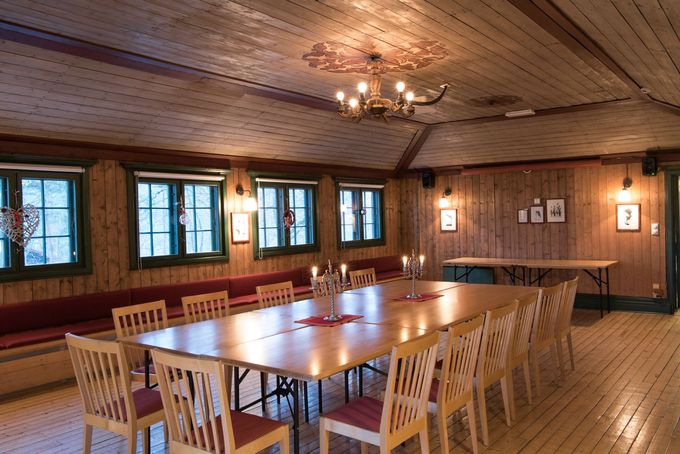 Spisesal med trepanel, langt bord, stoler og vinduslys.