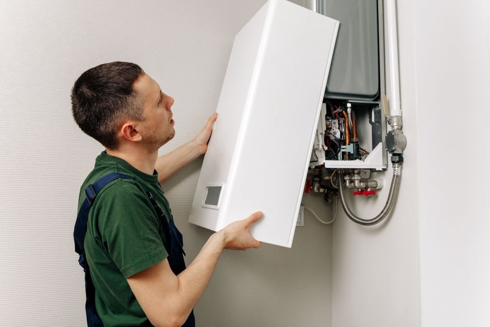 A man is fixing a boiler in a bathroom.
