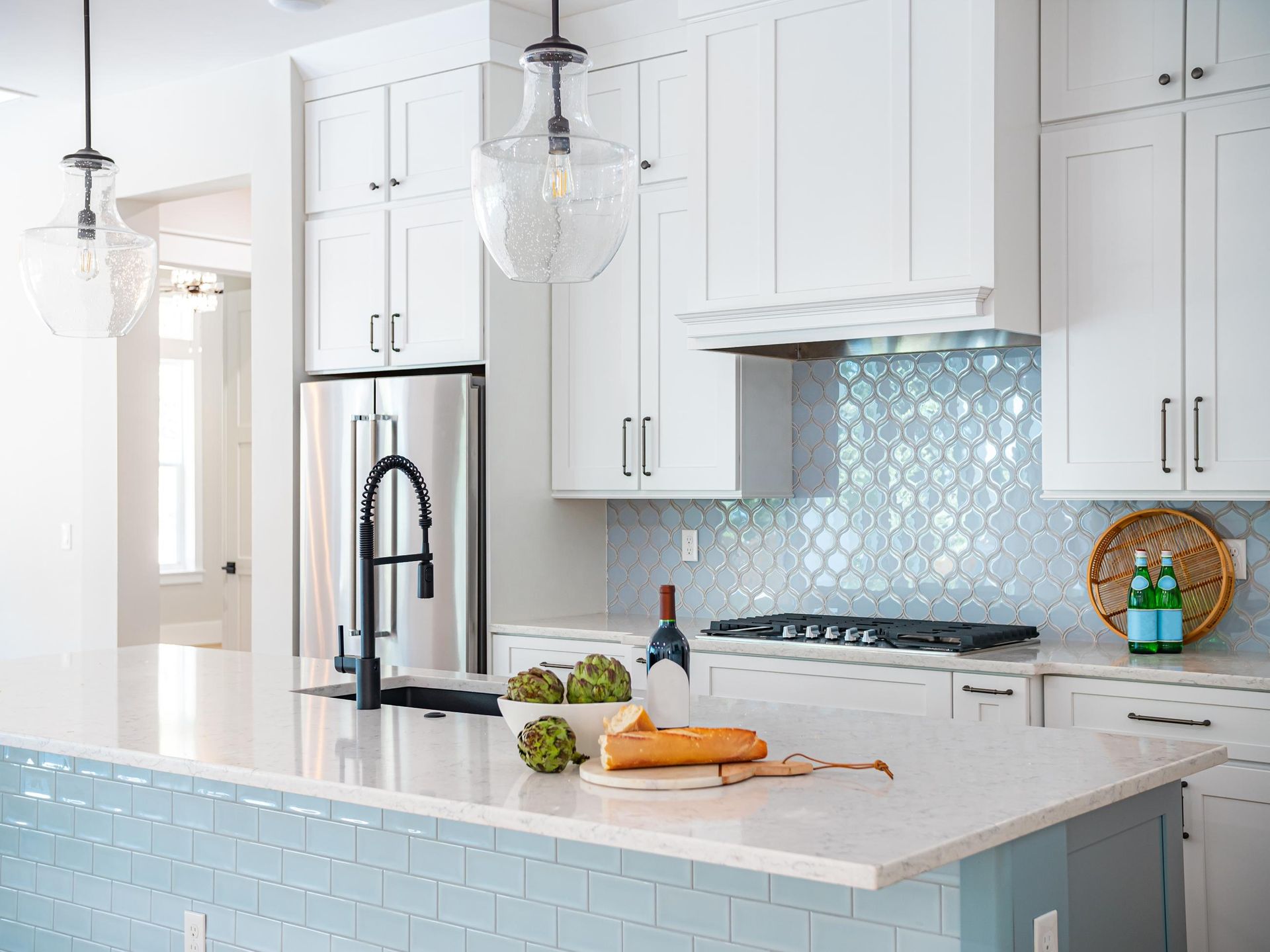 A kitchen with white cabinets , a stove , a refrigerator , a sink , and a large island.