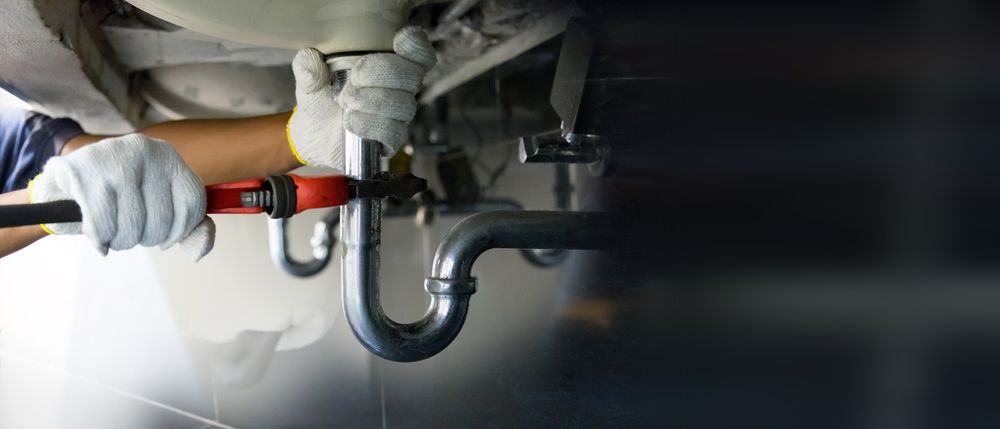 A plumber is fixing a sink with a wrench.