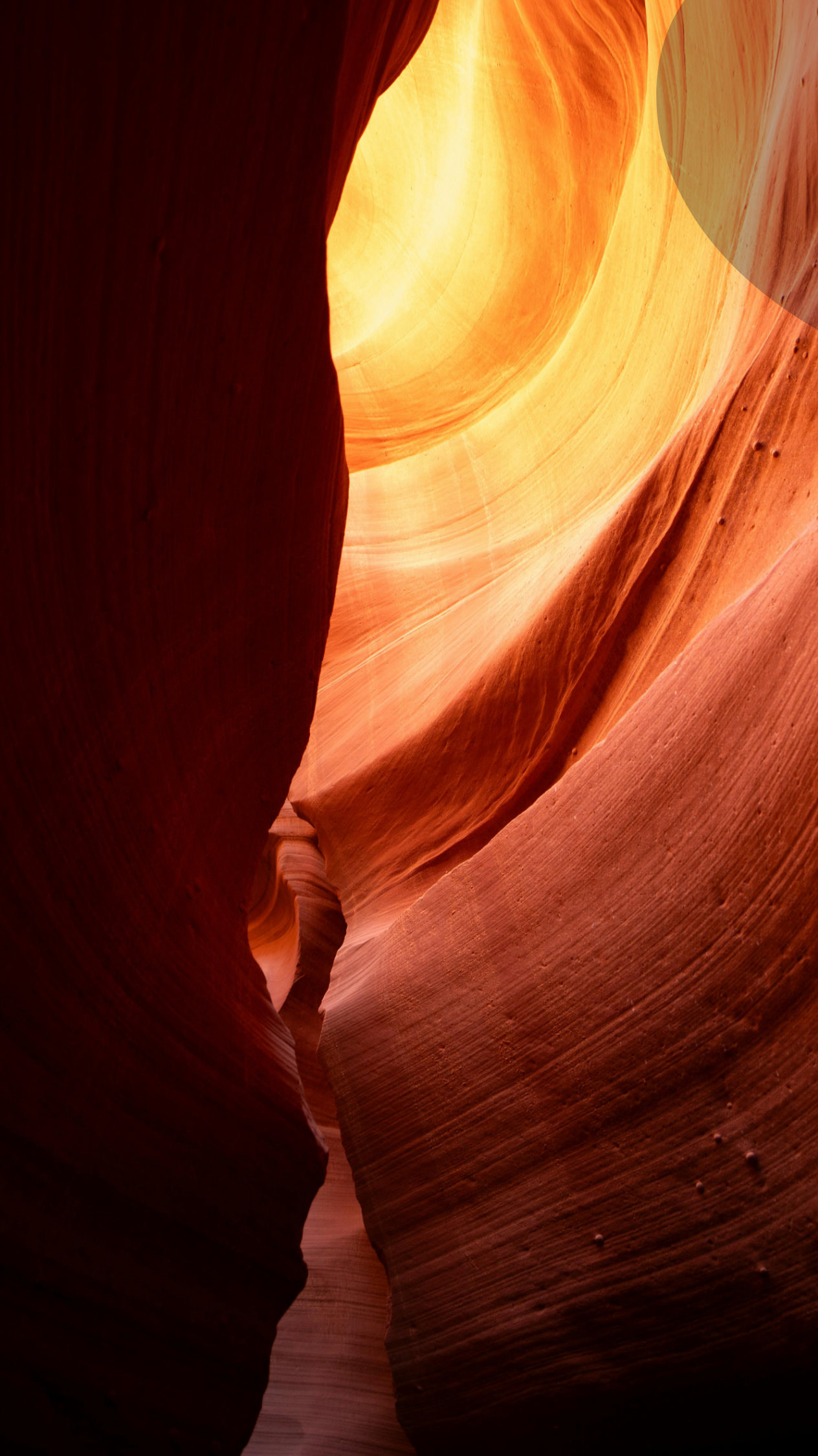 Sunlit red-orange sandstone canyon walls with a narrow glowing opening above