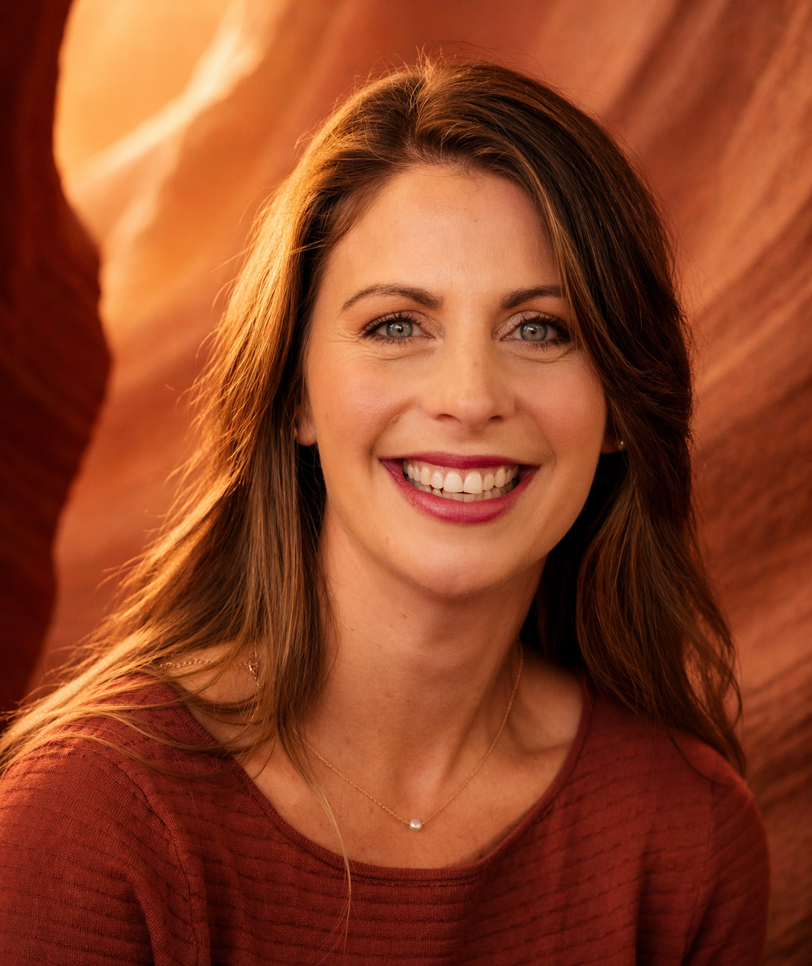 Smiling woman in a rust-colored top against a warm orange backdrop