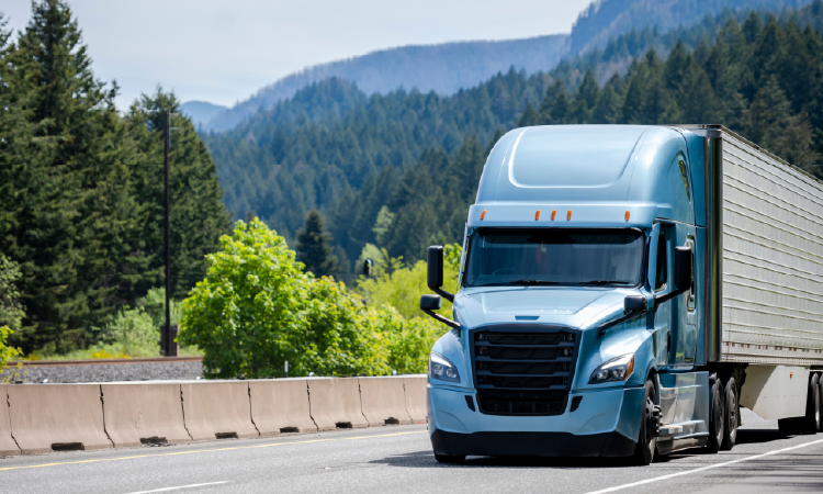 Light blue refrigerated semi-truck hauling temperature-controlled freight through mountain highway.