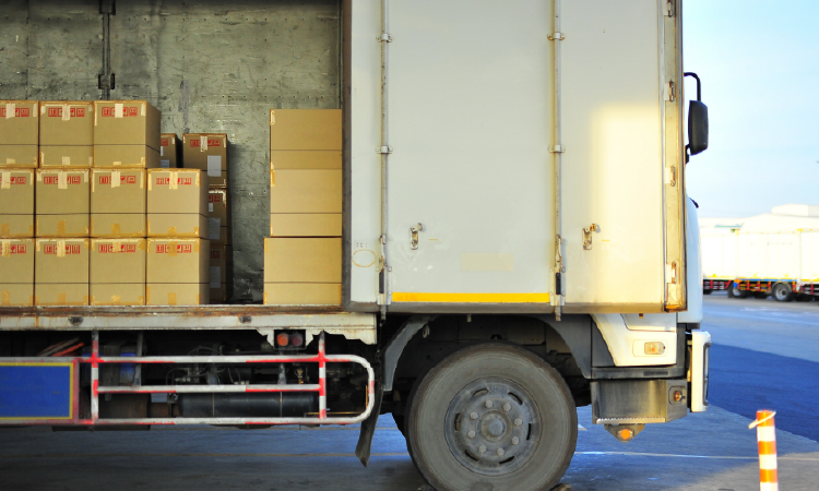 Boxes of temperature-sensitive freight loaded inside refrigerated delivery truck at warehouse dock.