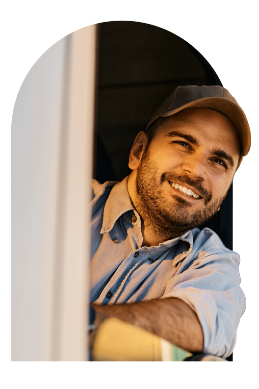 Smiling truck driver looking out from cab window during refrigerated freight delivery.