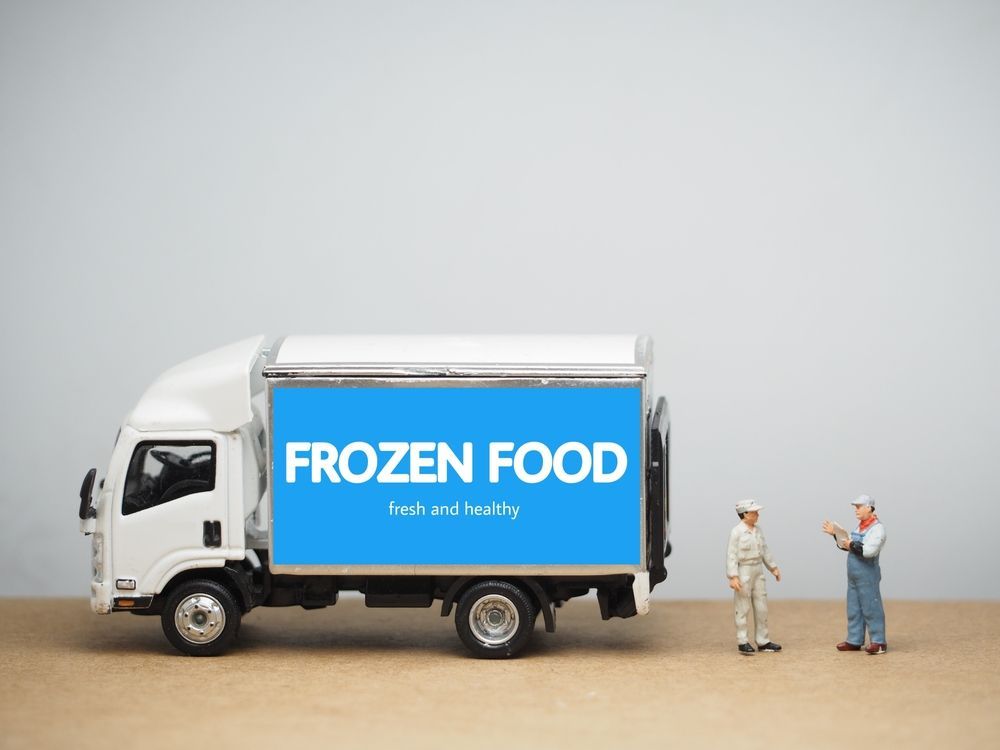 Miniature frozen food truck with two worker figurines on tabletop scene