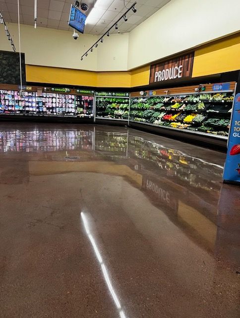 Empty grocery store produce section with shiny brown floor, bright overhead lights, and yellow and brown walls.
