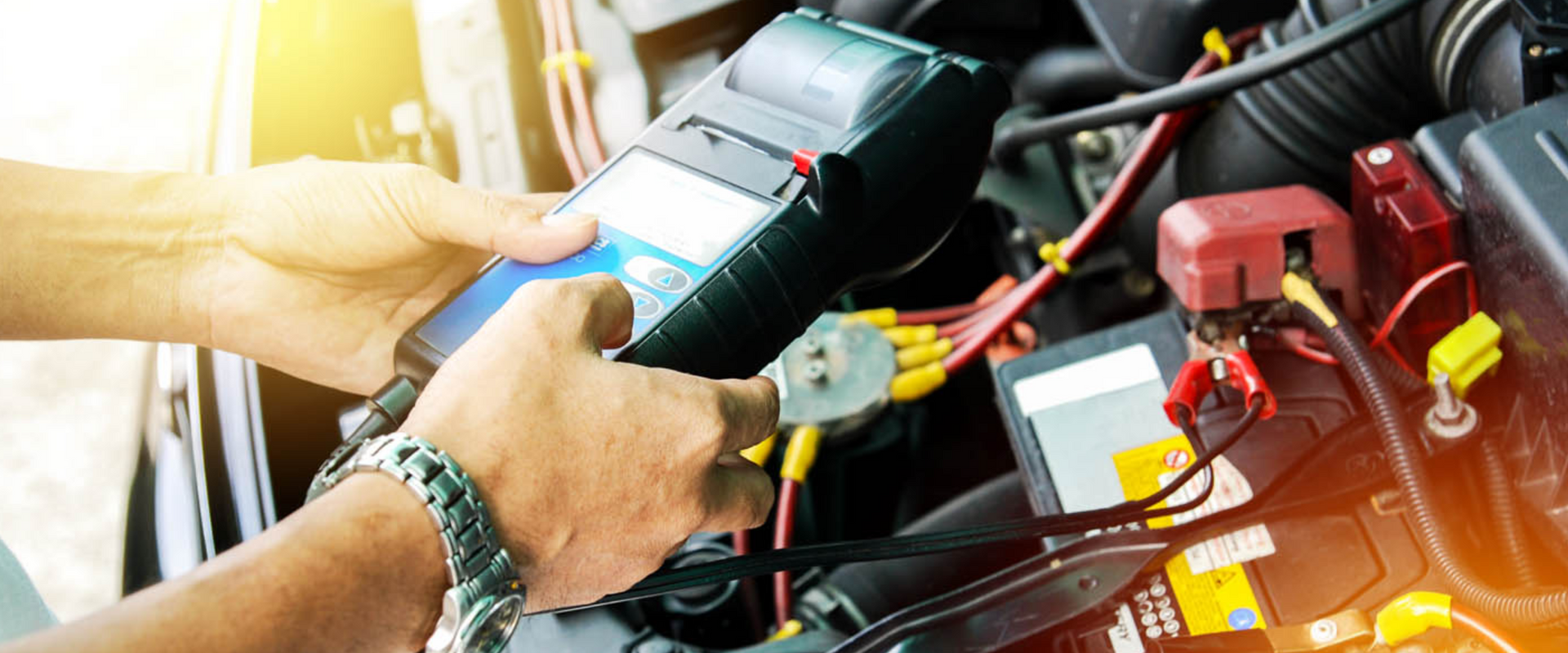 A picture of a technician testing a cars charging system and battery to make sure there are no issues.