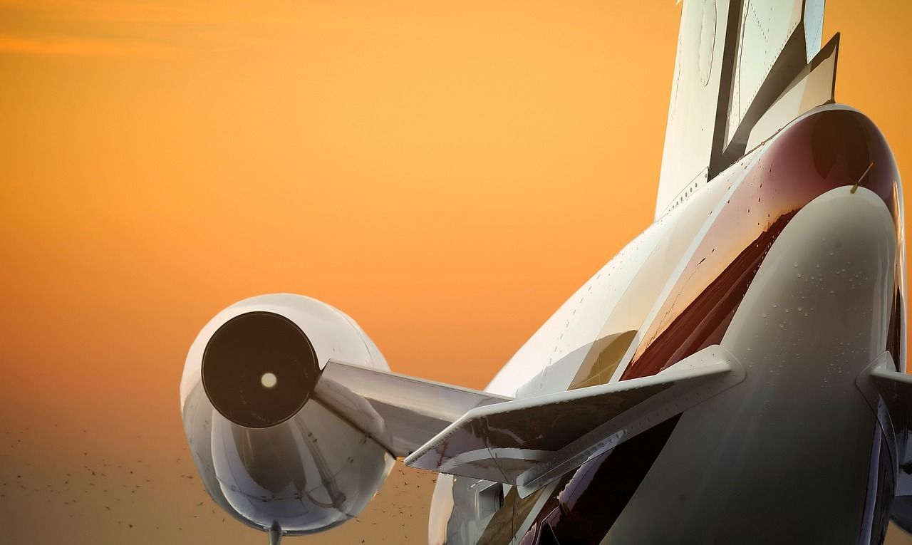 A close up of a plane 's tail with a sunset in the background