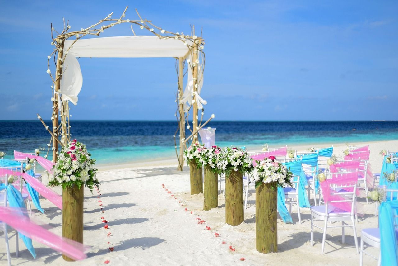 A wedding ceremony is taking place on a tropical beach.