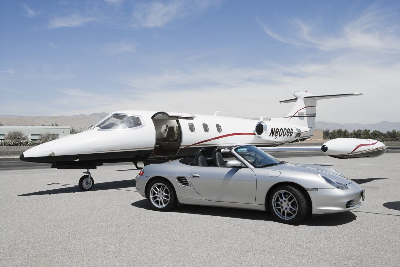 A silver car is parked next to a small plane with the letters nm53n on it