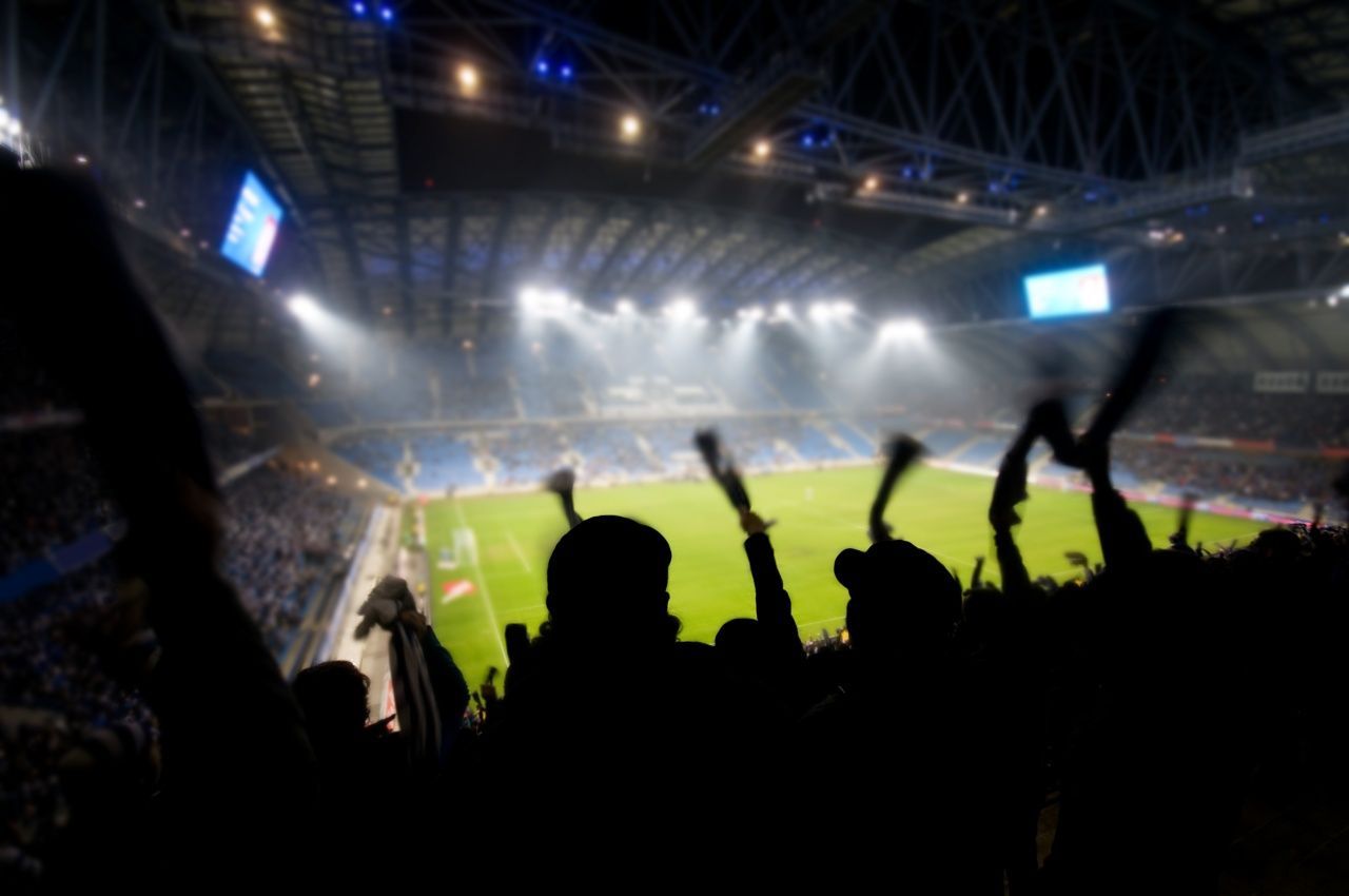 A crowd of people are watching a soccer game in a stadium.