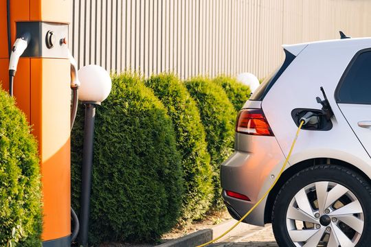 a white car plugged in to an orange building