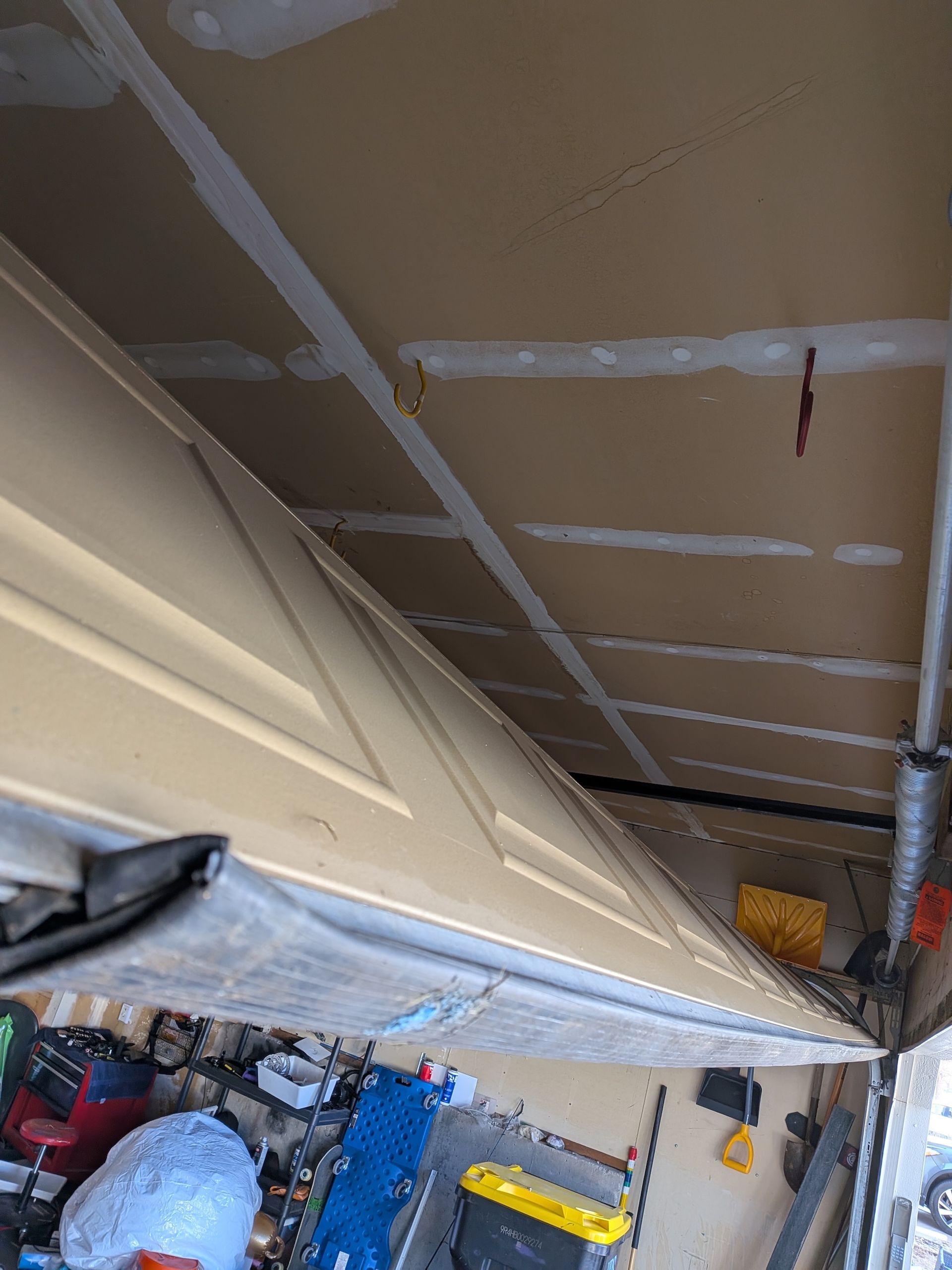 Low-angle view of an open garage door showing the underside of the panels and the unfinished drywall ceiling above.