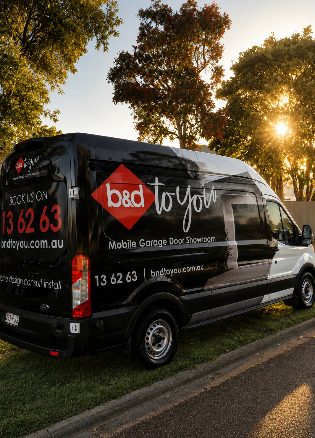 Black mobile garage door van with a red diamond logo and white “bad to…” lettering parked outside