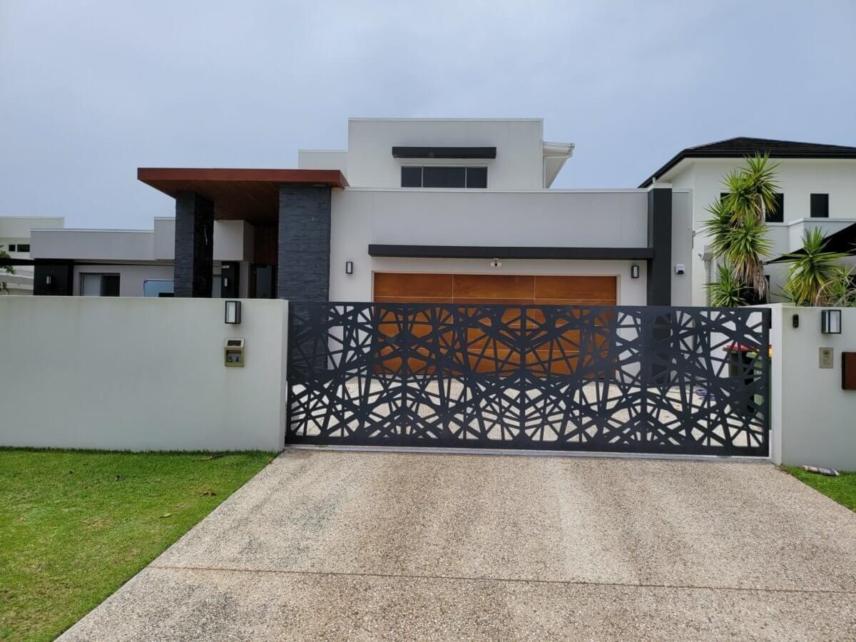 Modern house exterior with white walls, a black patterned gate, and a driveway in front