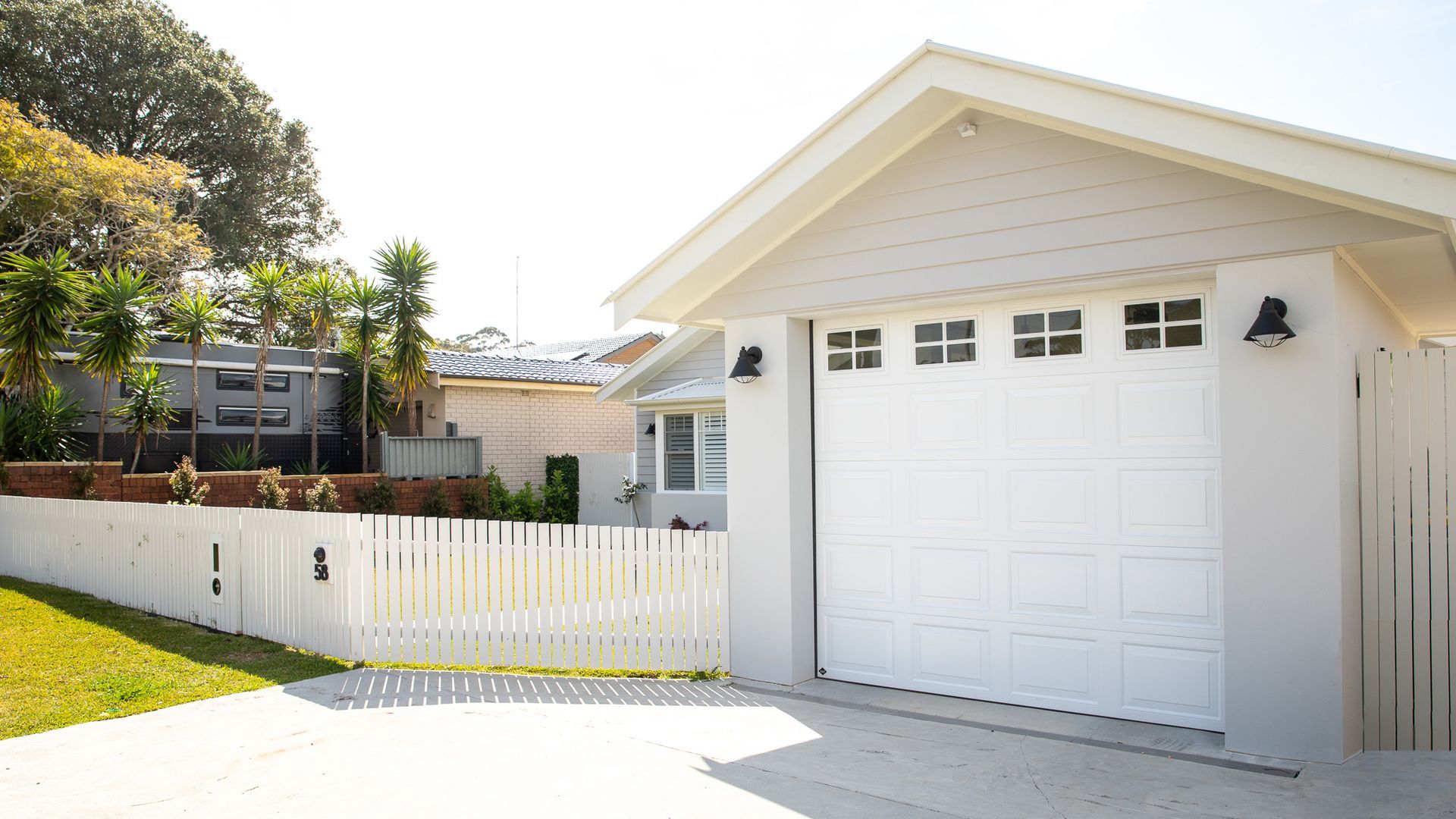 Hand opening a small garage door remote beside a closed white garage door