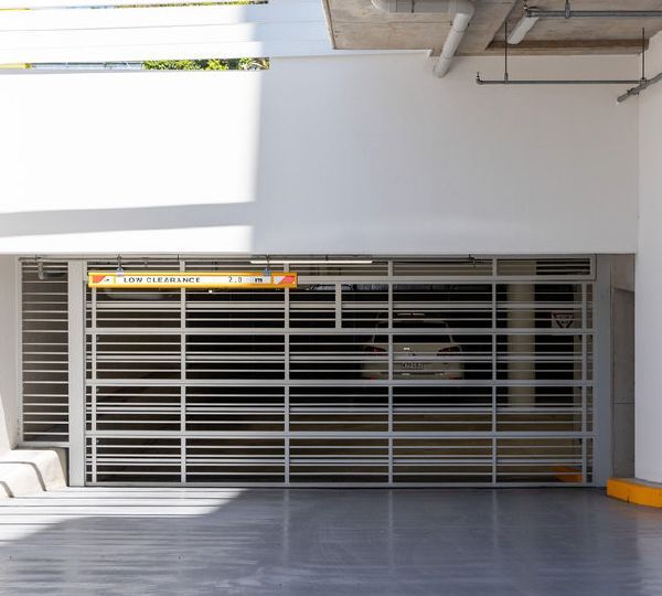 Closed white metal storefront shutter on a beige building facade