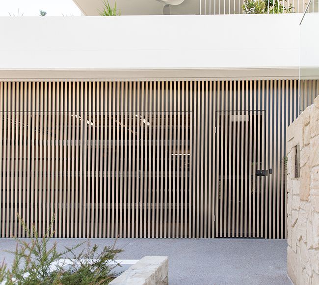 Modern house facade with dark wood siding, concrete column, and desert landscaping