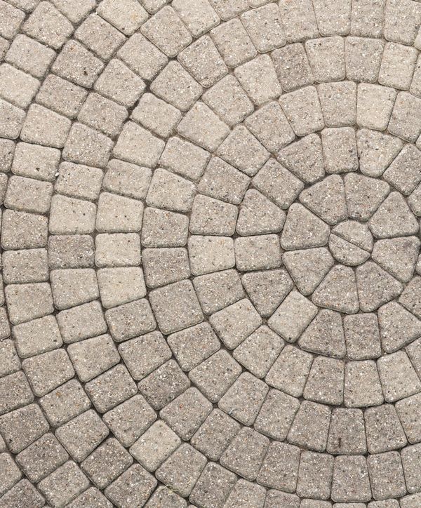 Beige stone pavers arranged in a repeating circular pattern, forming a decorative patio or walkway surface.