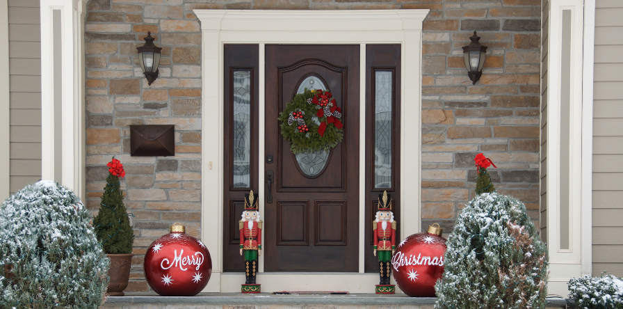 A decorated front door for Christmas with ornaments, nutcrackers, and a wreath.