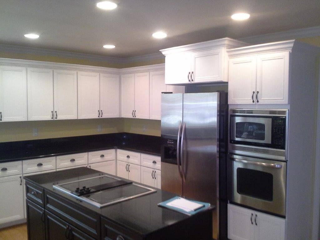 Kitchen with white cabinets, black granite countertops, a central island, and stainless steel appliances.