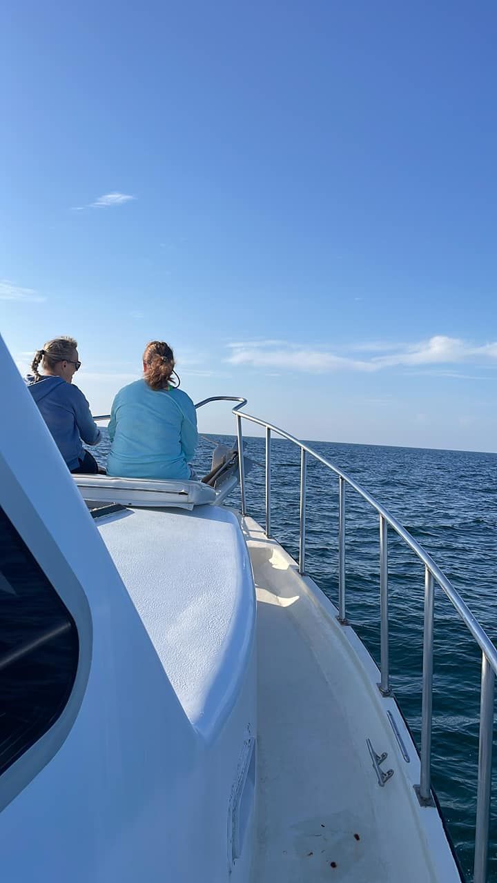 Two people are sitting on the back of a boat in the ocean.