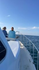 Two people are sitting on the back of a boat in the ocean.