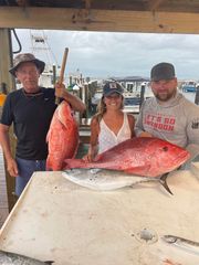 A group of people standing next to each other holding large fish.