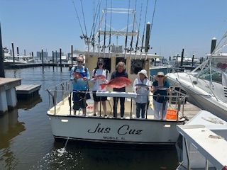 A group of people are standing on a boat holding fish.