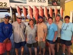 A group of people are posing for a picture with a bunch of fish.
