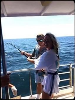 A man and a woman are fishing on a boat in the ocean.