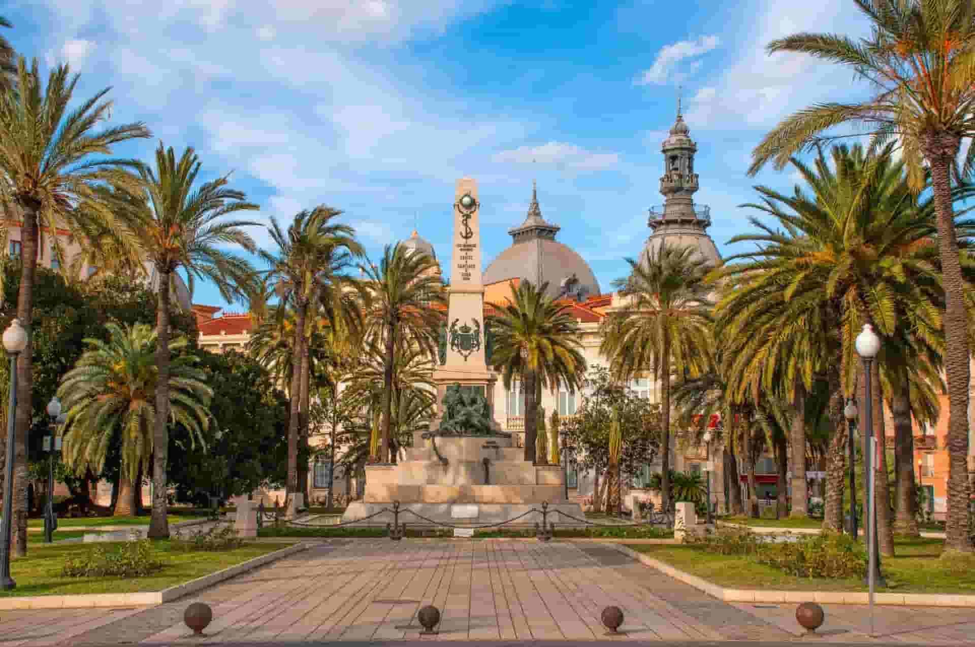 There is a statue in Cartagena in the middle of a park surrounded by palm trees.
