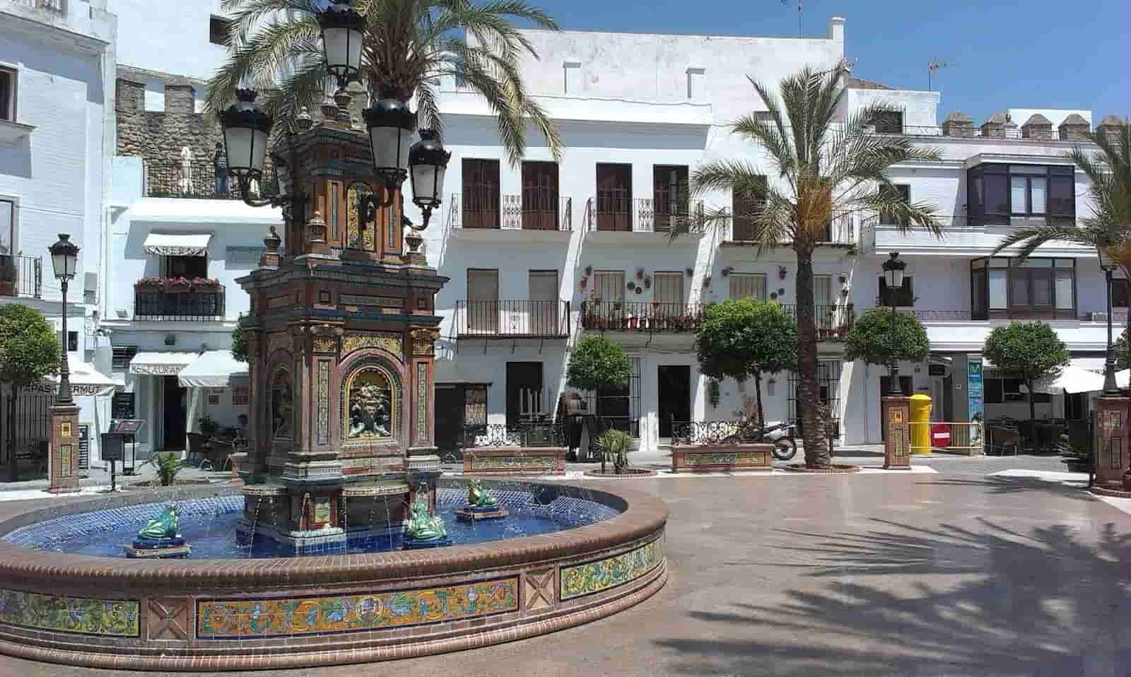 A fountain in a square in front of a white building
