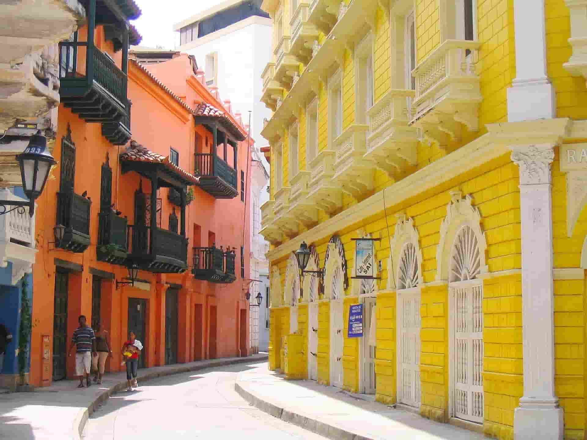 A narrow street with yellow and orange buildings on both sides in Cartagena.