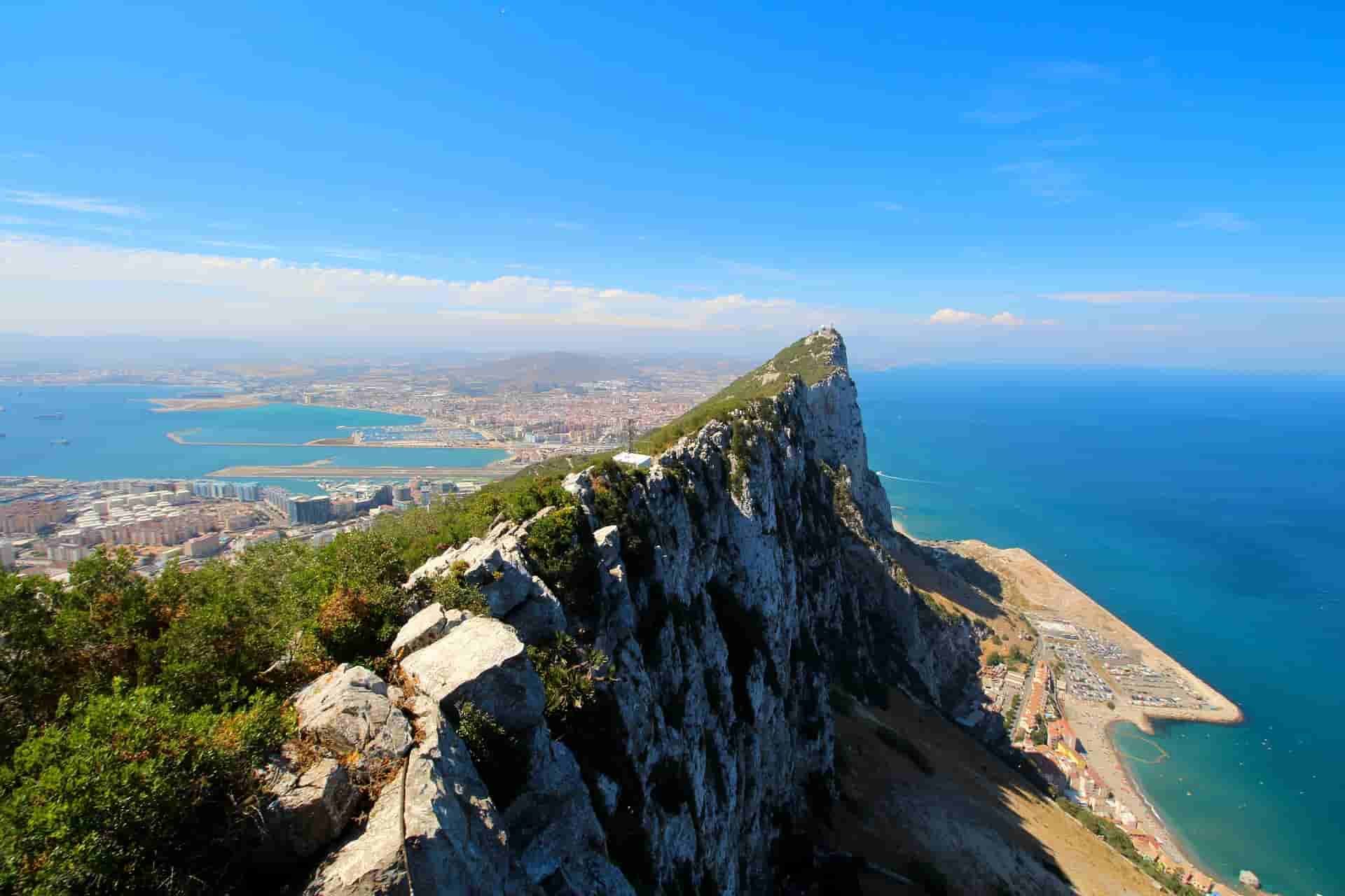 A sailboat is floating in the ocean with Gibraltar in the background.