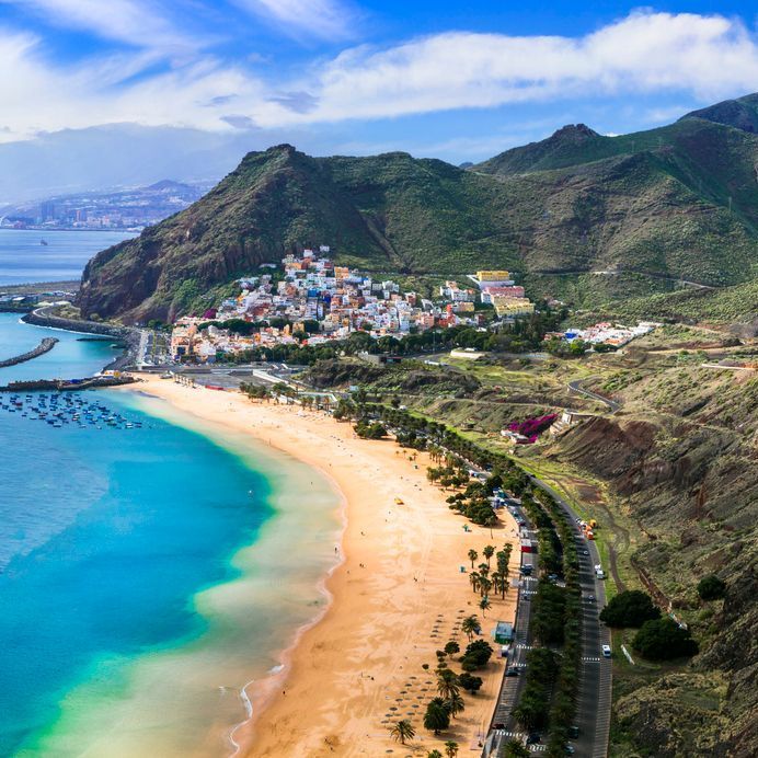 An aerial view of a beach with mountains in the background.